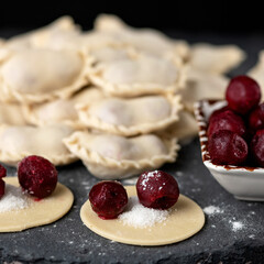 Cherry Dumplings, Cooking process. Red berry and sugar filling on rolling Raw dough circles in foreground. Close up shot. Ingredients to making delicious Convenience Food. Square format 1x1.