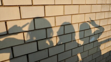 shadow of 3 lady on the brown tile wall