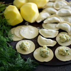 Dumplings Cooking process. Dill and potatoes filling on rolling Raw dough. Ingredients to making of Convenience Food on kitchen table. Square format 1x1. Soft focus. Top view.