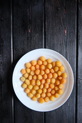 Ripe yellow raspberry lies on a white plate on a black background. Top view. Copy space.