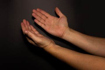 The man whose hand is praying on the dark background, selective focus.