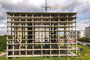 Aerial view of high tower crane and residential apartment buildings under construction. Real estate development.