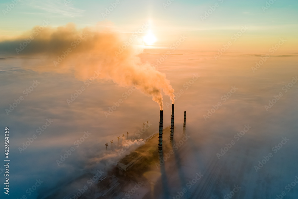 Poster aerial view of coal power plant high pipes with black smoke moving up polluting atmosphere at sunset