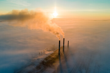 Aerial view of coal power plant high pipes with black smoke moving up polluting atmosphere at sunset. - obrazy, fototapety, plakaty