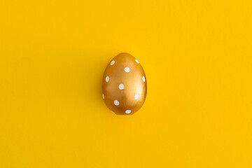 Golden egg on a yellow background. Minimal easter concept.