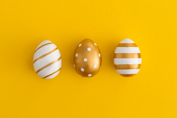 Golden eggs on a yellow background. Minimal easter concept.