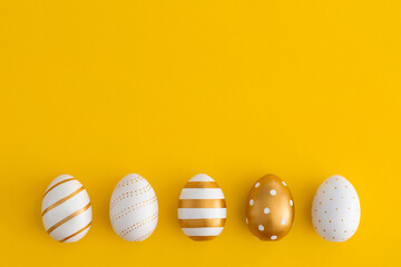 Golden eggs on a yellow background. Minimal easter concept.