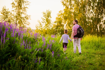 a male tourist with a backpack and a boy, happy children in light clothes on the path in the park, a summer concept and a happy free childhood