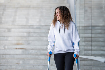 girl with crutches walking alone, head-on