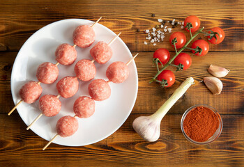 Meat balls on a white plate. Cherry tomatoes, garlic, spices. Wooden table. Top view.