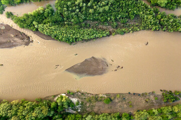 Aerial view of wide dirty river with muddy water in flooding period during heavy rains in spring.