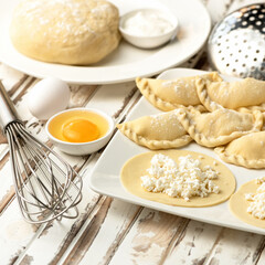 Process of making sweet dumplings with cottage cheese. Rolled raw dough stuffed with cottage cheese on kitchen table, top view. Homemade preparations and semi-finished products concept.