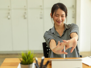 Female office worker stretching her arms, relaxing in comfortable office room