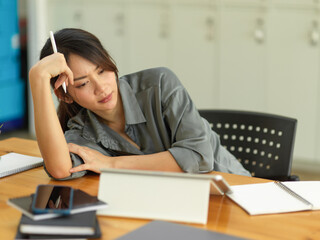 Female feeling upset while working with digital tablet and office supplies in office room
