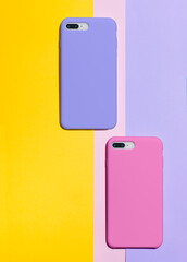 Bright phone cases mock up. Pink and purple smart phone cases back view lie on a background of...