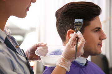 Professional hairdresser dying hair in beauty salon, closeup