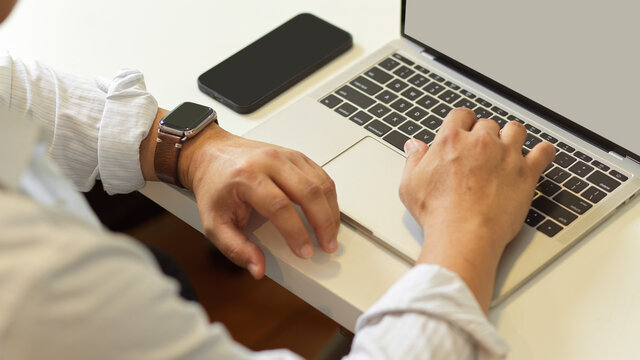 Male Hands Working With Laptop On White Desk With Smartphone In Home Office Room