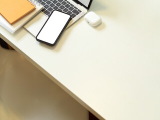 Creative workspace with smartphone, laptop, notebooks and copy space on white table
