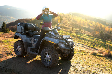 Happy woman driver in protective helmet enjoying extreme riding on ATV quad motorbike in summer...