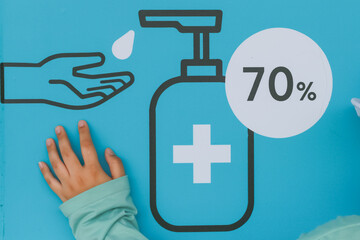 Close-up wall sign, recommend using hand sanitizer. For cleaning and preventing viruses. Blue background And a woman's hand