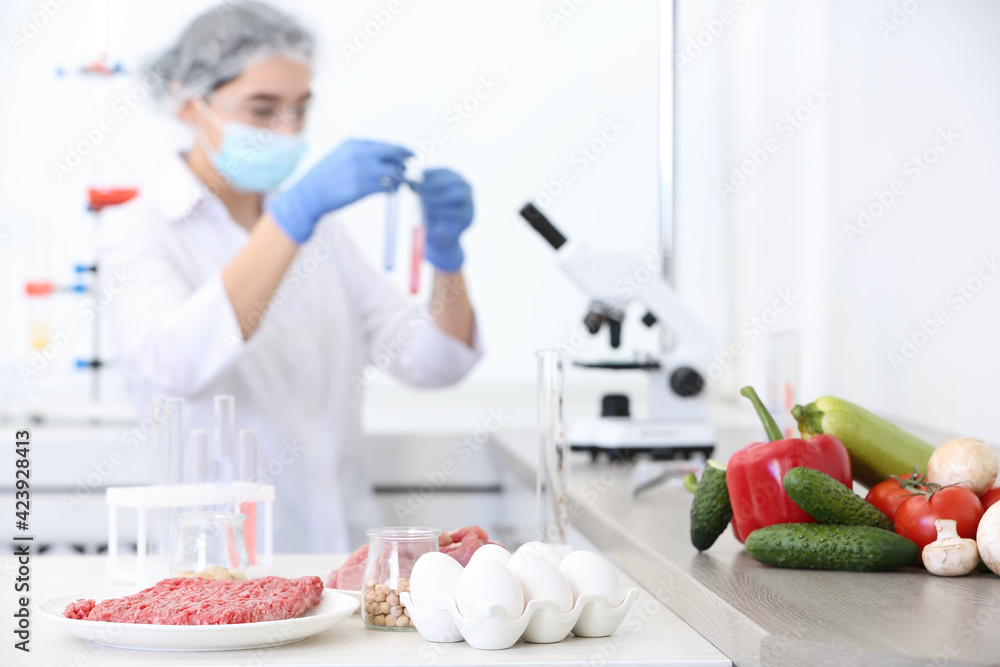 Wall mural different food on table and scientist proceeding quality control in laboratory