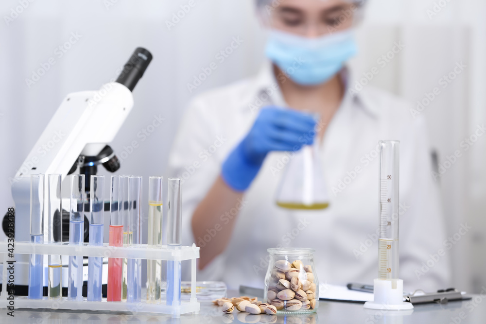 Wall mural pistachios on table and scientist proceeding quality control in laboratory
