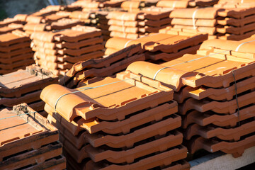 Stacks of yellow ceramic roofing tiles for covering residential building roof under construction.