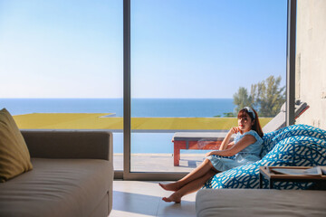 Fototapeta premium Portrait woman relaxing enjoying luxury lifestyle on blue soft sofa at home. Beautiful young lady Asian Caucasian female model, thinking looking happy up smiling cheerful of stress free weekend.