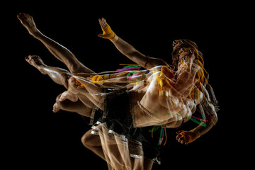 Young man thai boxer training over dark background in neon mixed light.