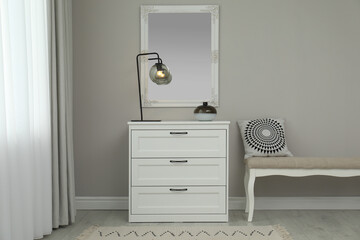 Hallway with stylish chest of drawers and mirror. Interior design