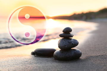 Stack of stones on sandy beach and Ying Yang symbol. Feng Shui philosophy