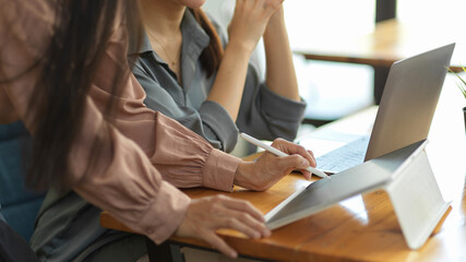 Side view of female office worker sharing her idea on digital tablet to her coworker
