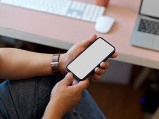 Close up view of businessman relaxed sitting at workplace and using smartphone
