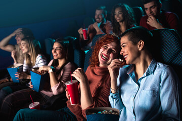 Group of cheerful people laughing while watching movie in cinema.