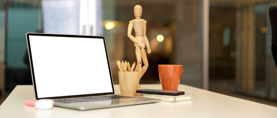 Home office desk with laptop , wooden figure, coloured pencils and supplies