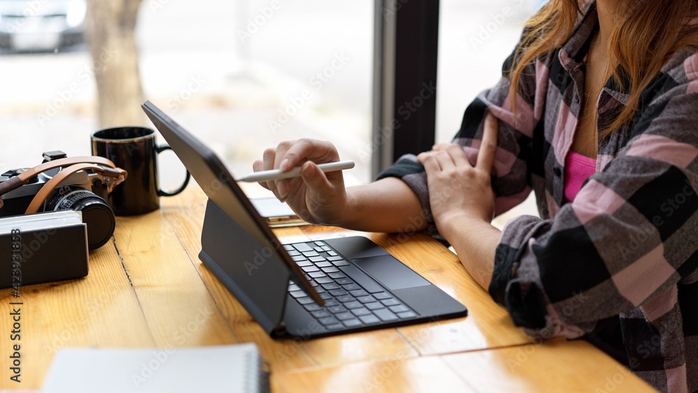 Poster side view of female working with tablet while sitting in workspace