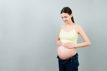 pregnant belly at colorful background with copy space. Expecting mother in opened jeans. Motherhood concept