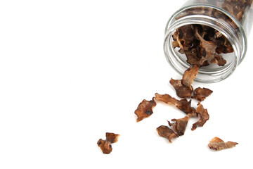 Dried tamarind slices in a glass jar and scattered on ground isolated on white background