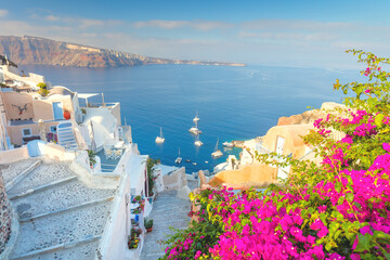 Narrow street with flowers, traditional Greek houses and a staircase to the sea, Santorini, Greece