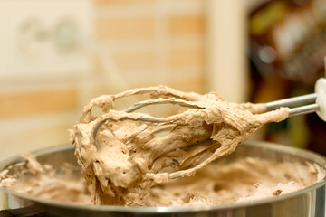 Closeup of electrical blender whipping in bowl chocolate cream for cake, ice cream or dessert. Kitchen bakery equipment, homemade baking.