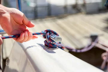 Foto auf Acrylglas Human hand on sailing boat or yacht tying a knot, close up view © lenaivanova2311