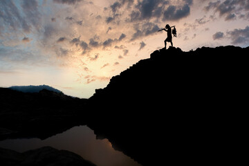 The silhouette of a young man who fishes a fish climbs a mountain big fish Concept of personal development and goals in life The background is beautiful sky.
