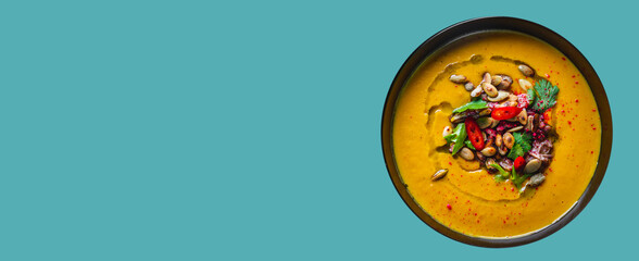 Pumpkin soup in black plate on blue background