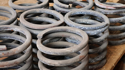 Group of metal springs of shock absorbers on wooden palete. Spare parts of heavy industrial machinery.