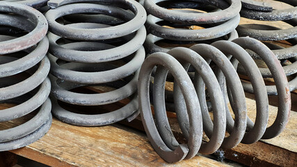 Many steel springs of shock absorbers on wooden palete. Spare parts of heavy industrial machinery.