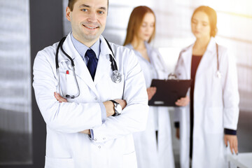 Professional middle aged doctor with a stethoscope and crossed arms at work in a sunny clinic. Perfect medical service in a hospital. Medicine and healthcare concept