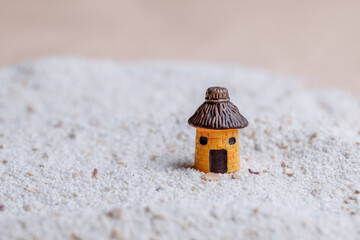 A miniature house and a landscape of white sand with stone and shells. Small toys.
