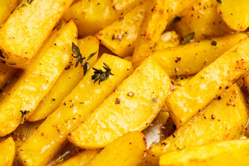 Sliced grilled potatoes with spices and herbs on the pan. Selective focus. Shallow depth of field.