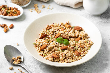 Homemade organic nut granola in a ceramic plate on a light background. Baked oatmeal muesli with almonds, walnuts, hazelnuts and pumpkin seeds close-up