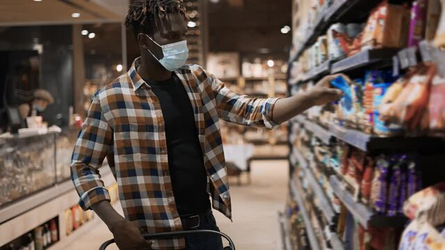 African american guy taking products from the shelf in the supermarket